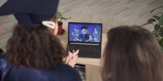网上毕业典礼，兴高采烈的家长和女学生一起用笔记本电脑上的现代技术和视频通信在线庆祝大学毕业