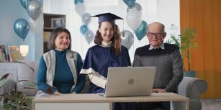 在线毕业，在盛大的毕业典礼上，快乐的父母通过视频连接坐在家里的笔记本电脑上，给女儿颁发毕业证书