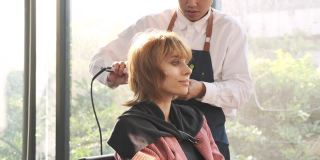 美发师在美容院用小吹风机为漂亮的白人女性做头发。