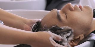 理发师的手正在用香波和按摩为男顾客洗头。