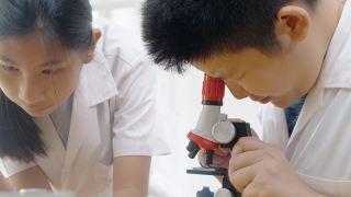 亚洲儿童穿着实验服，用显微镜做科学实验，在家学校实验室，教育生活理念。视频素材模板下载
