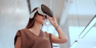 亚洲程序员女性女性戴着vr护目镜3d可视化行走和探索在元宇宙未来的生活方式在现代办公背景下，新常态技术虚拟数字世界探索