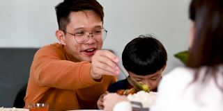 中国农历新年，一名亚洲男子在家中享用团圆饭时，与母亲分享食物