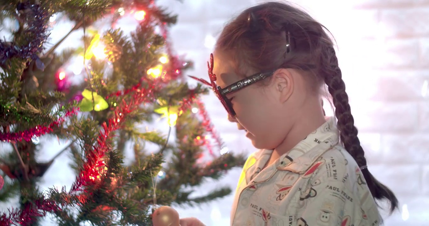 快乐的亚洲小女孩在圣诞节装饰圣诞树