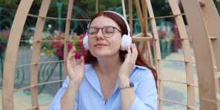 白人英俊的年轻女子戴着耳机，听着音乐在城市公园在日落