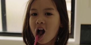 混血亚裔女孩早上在浴室刷牙，儿童口腔健康