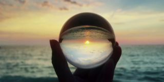 手握魔法水晶球在美丽的自然景观日落，旅游理念