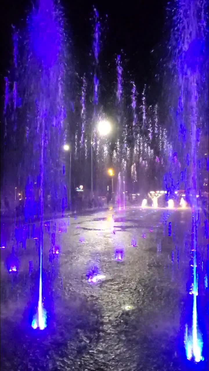 现代歌唱喷泉在城市广场，在晚上的公园。彩色歌唱喷泉特写，孩子们在夏天可以在上面奔跑