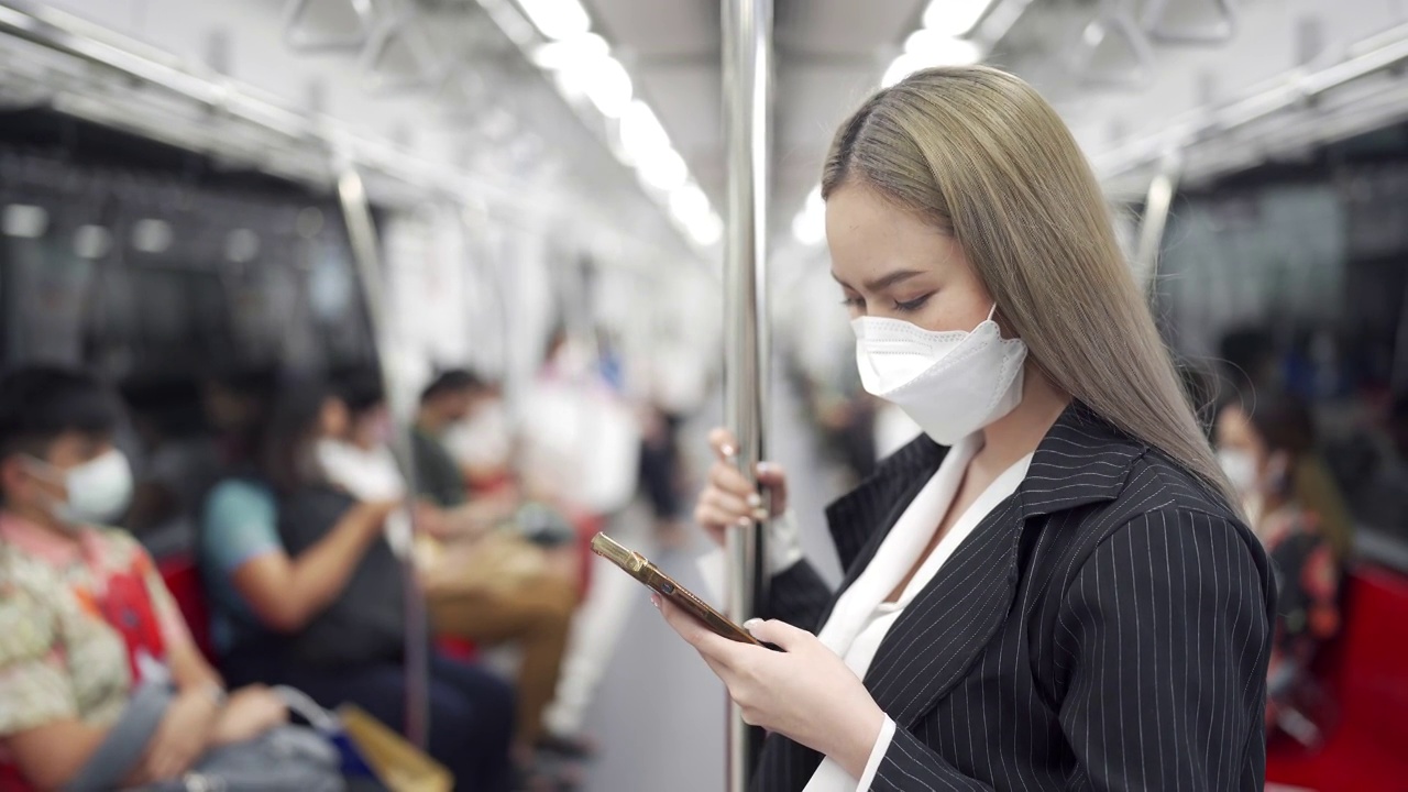 2019冠状病毒病大流行期间乘坐地铁时使用智能手机的女商人