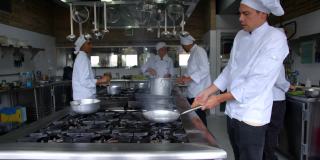 拉丁美洲的厨师在商业厨房烹饪，并在平底锅中烹制sautéing食物