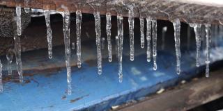 冰柱悬挂在木板上和水滴上。第一次霜冻。气候变化的概念。春天的时间
