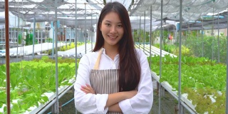 年轻的新一代亚洲女孩农民站在他的双臂交叉照顾蔬菜种植的农场，农业是可持续的农业健康食品。