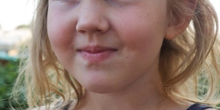 一个可爱的十几岁的女孩手里拿着许多新鲜的草莓，用鼻子嗅着草莓，把它带到脸上。缓慢的运动。特写镜头