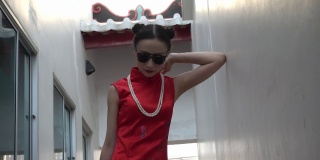 中国时装模特在旗袍传统中国服装和太阳镜作为中国匪帮。