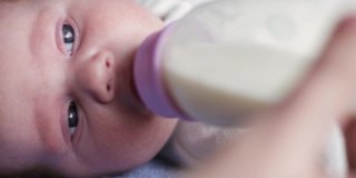 一个可爱的新生儿通过奶瓶被喂牛奶的特写