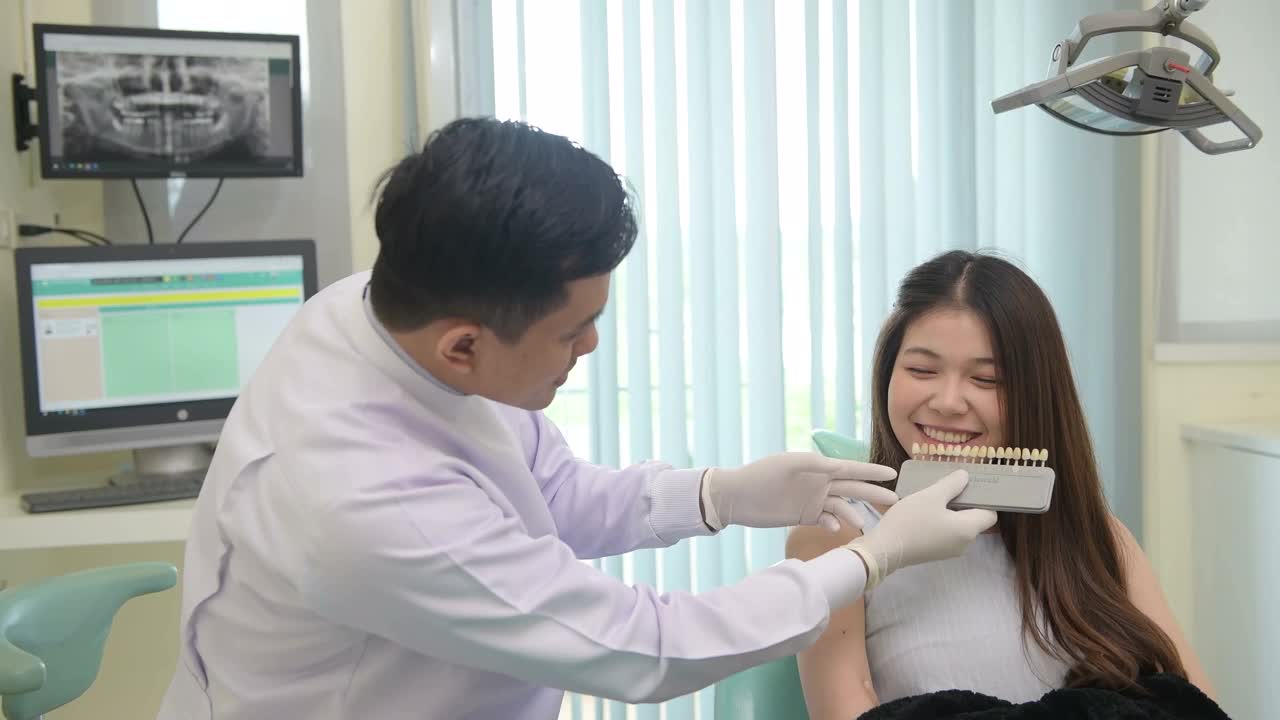 在现代牙科诊所为女性病人检查牙齿的男牙医