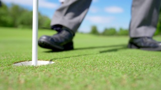 4K老年高尔夫球手在球道上将高尔夫球打入洞内视频素材模板下载