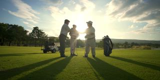 在夏日夕阳下的高尔夫球场上，亚洲男子高尔夫队结束比赛后握手致意