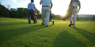在夏日夕阳下，亚洲商人和高级CEO一起拿着高尔夫球袋漫步在高尔夫球道上