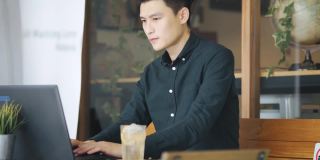 微笑的专业年轻亚洲中国商人工作使用笔记本电脑在露天咖啡馆