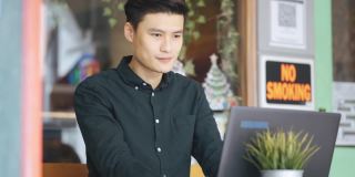 微笑的专业年轻亚洲中国商人工作使用笔记本电脑在露天咖啡馆