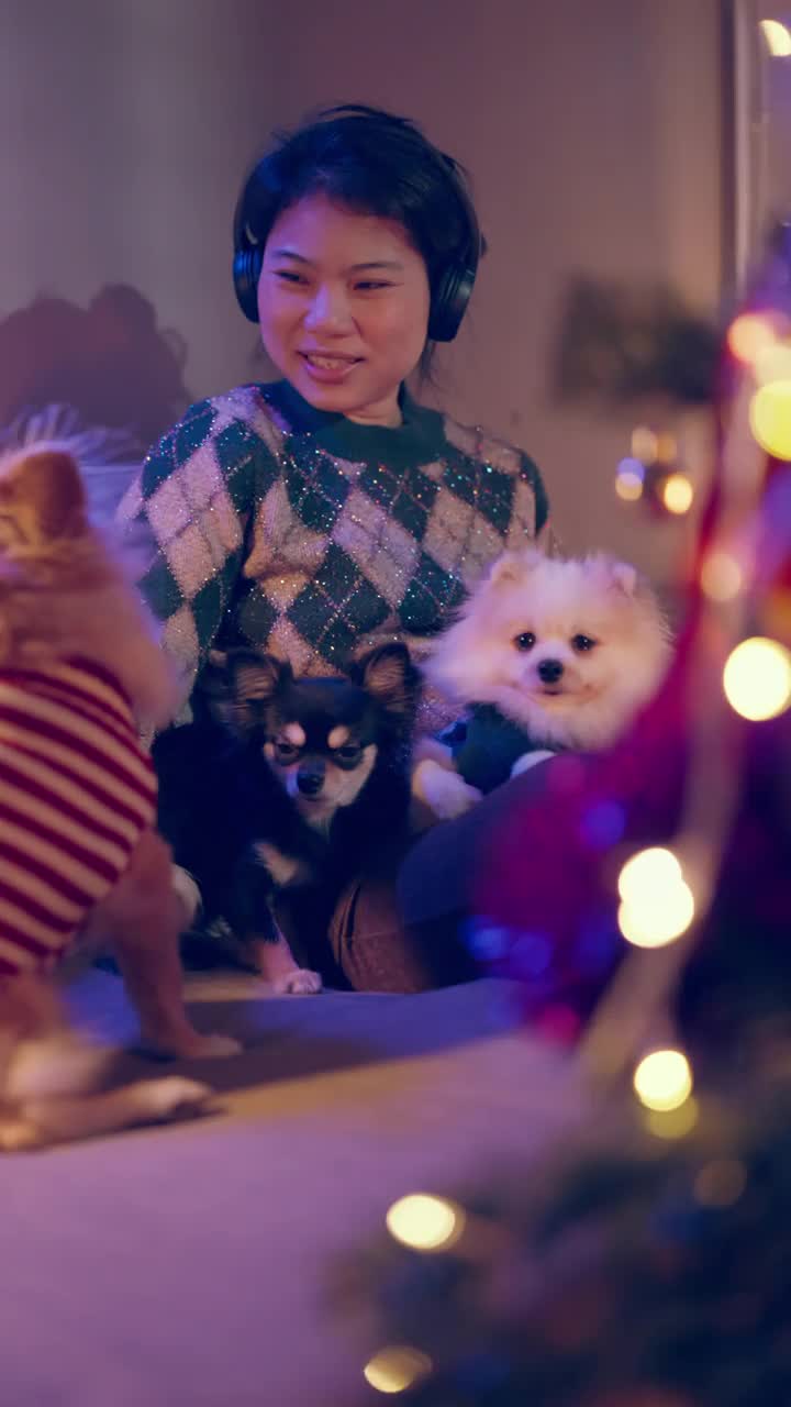 幸福圣诞假期与亚洲女性休闲毛衣坐放松阅读小说书与小哈巴狗坐在一起与蚬和快乐在客厅的家圣诞节日的想法概念垂直拍摄