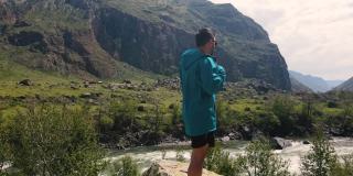 一个穿着蓝色夹克的男人站在悬崖边上。Katu-Yaryk峡谷Chulyshman山谷。阿尔泰