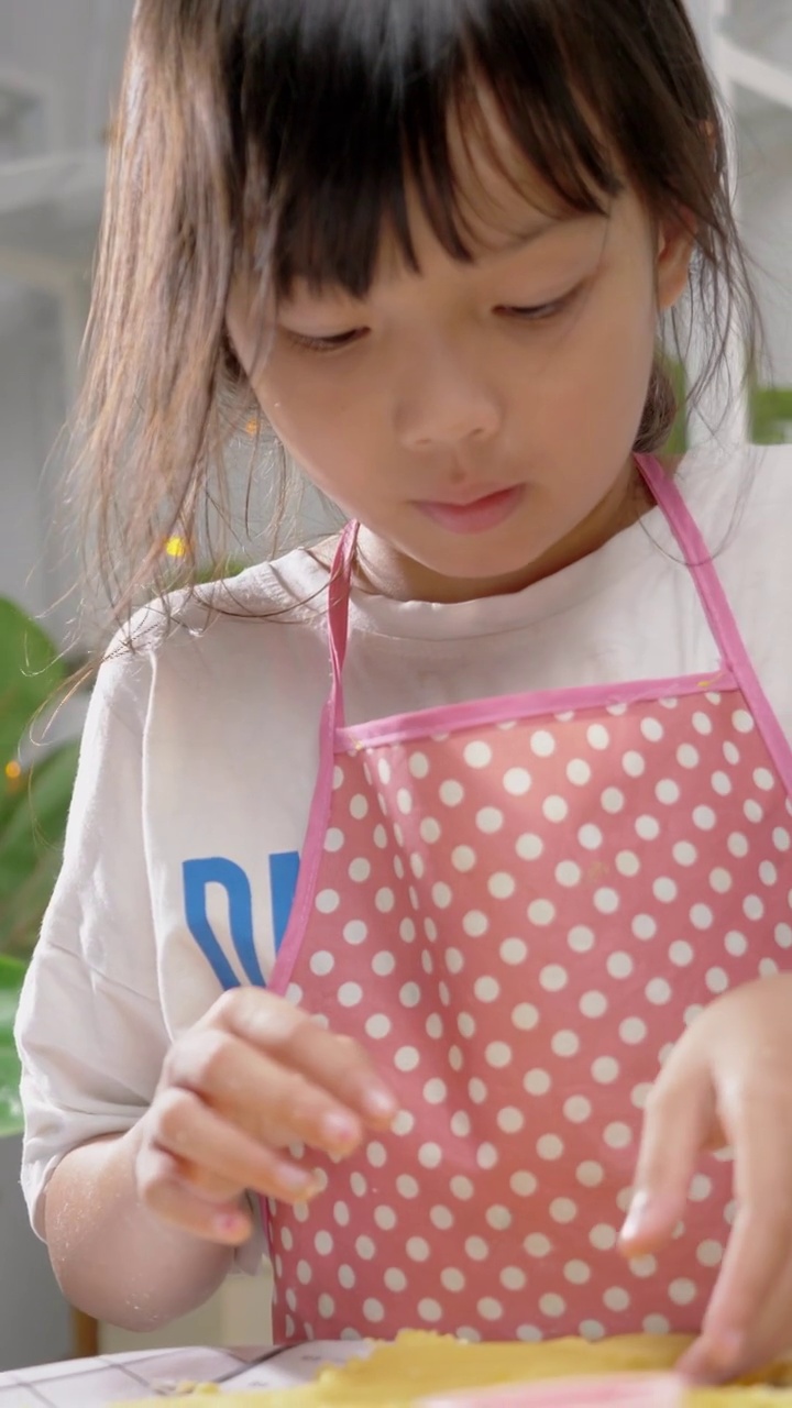 亚洲女孩用饼干切割机塑造自制饼干庆祝圣诞节，生活理念。
