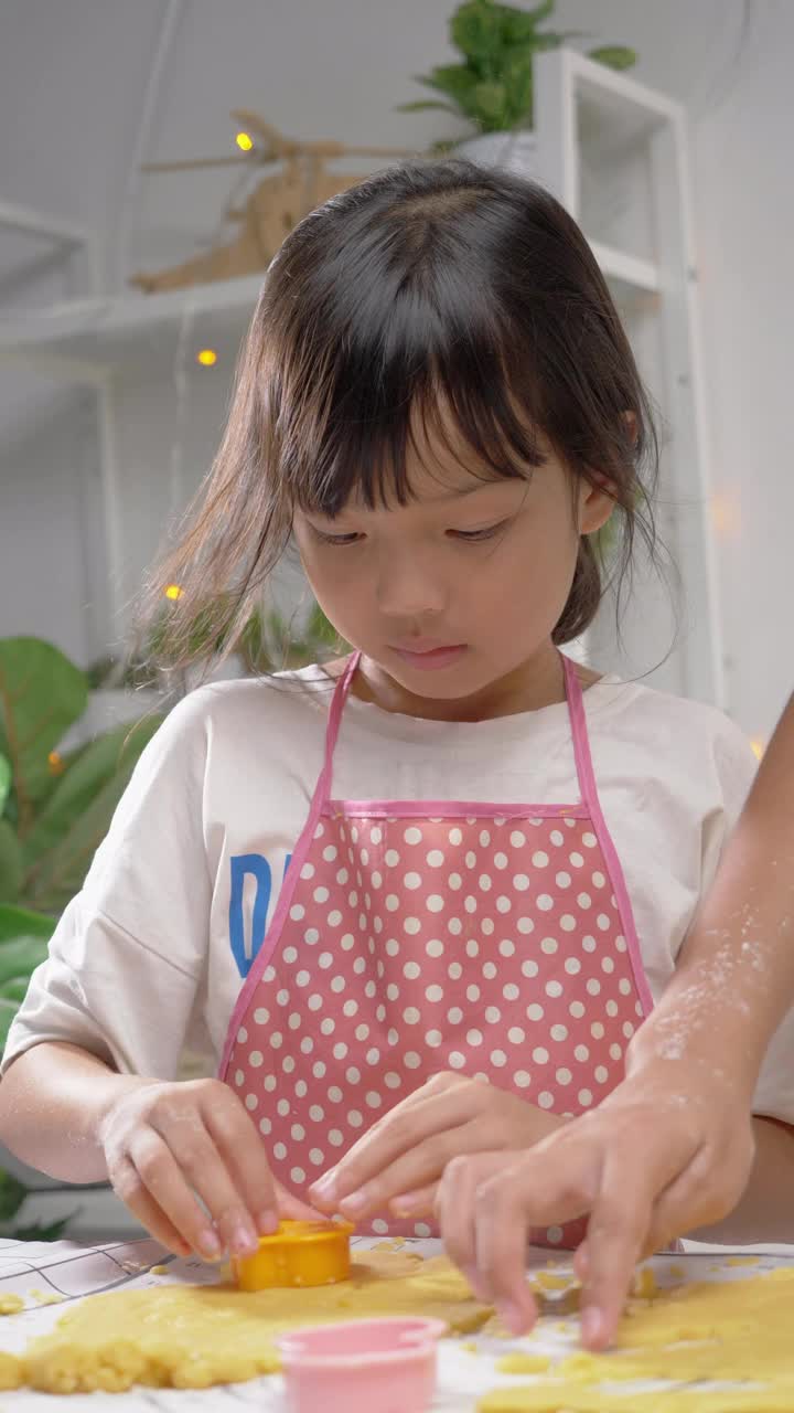 亚洲女孩用饼干切割机塑造自制饼干庆祝圣诞节，生活理念。
