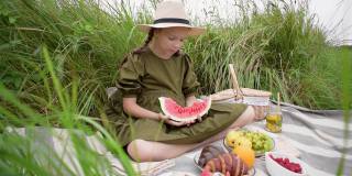 女孩在户外野餐吃一块西瓜。青少年度过他的空闲时间。健康心理健康概念。新鲜水果环保