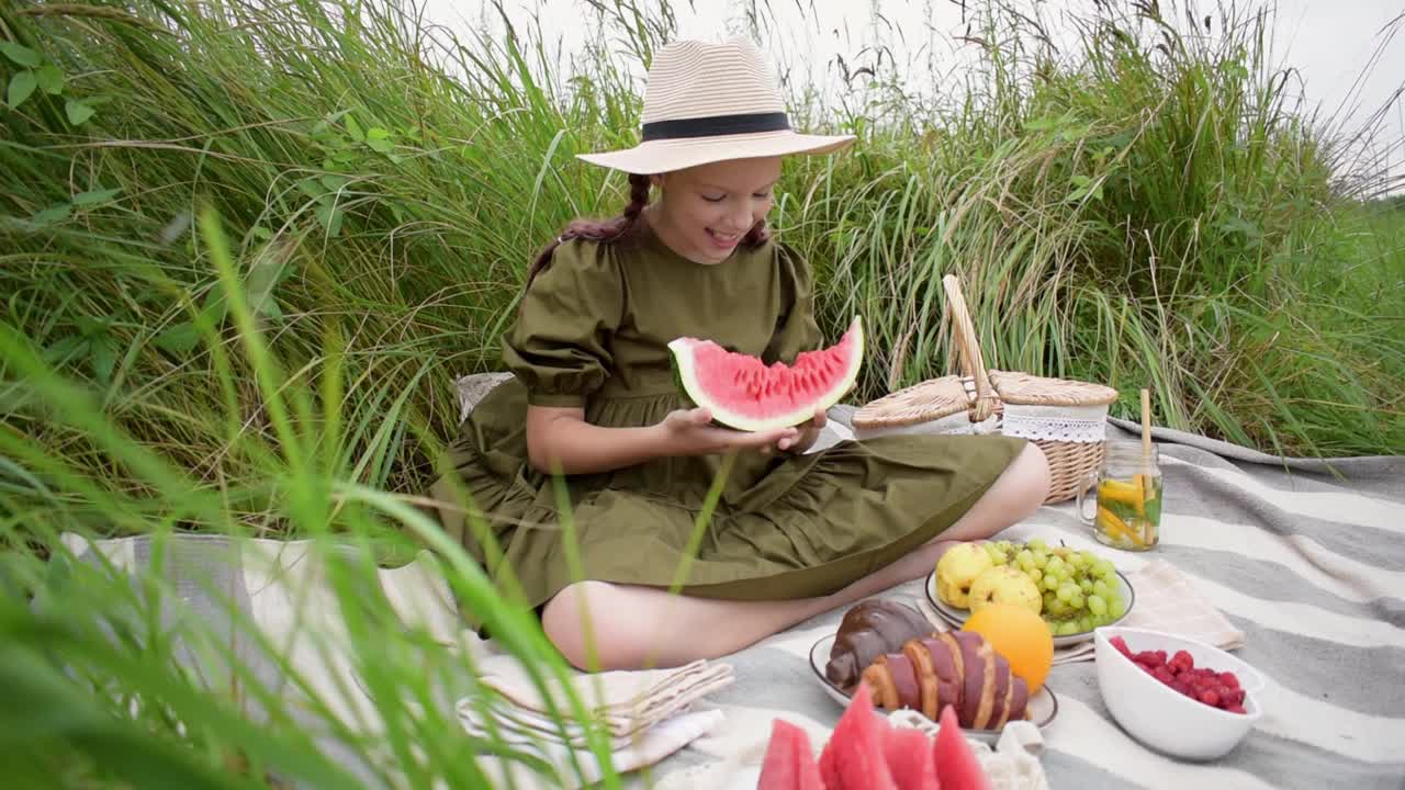 女孩在户外野餐吃一块西瓜。青少年度过他的空闲时间。健康心理健康概念。新鲜水果环保