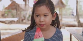 手持慢动作年轻混合亚洲女孩吃西瓜冰棒在炎热的夏天假期