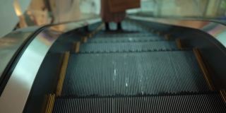 无法辨认的年轻女子上扶梯，下楼梯，迈步，在商场里向前走的特写镜头。