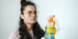 女清洁工的肖像转向相机在家里喷洒水和清洗