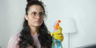 年轻妇女的肖像喷玻璃水和清洁布在室内工作