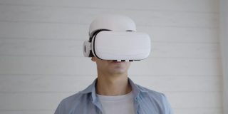 年轻的西班牙男子戴着虚拟现实玻璃触摸模拟屏幕在家里分析数据