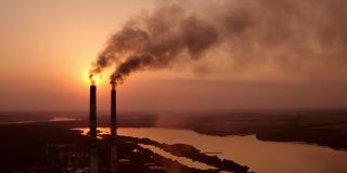 工业排放的有害气体污染空气。在日落时分，河流附近有烟筒的有害工厂。全球变暖。环境污染。