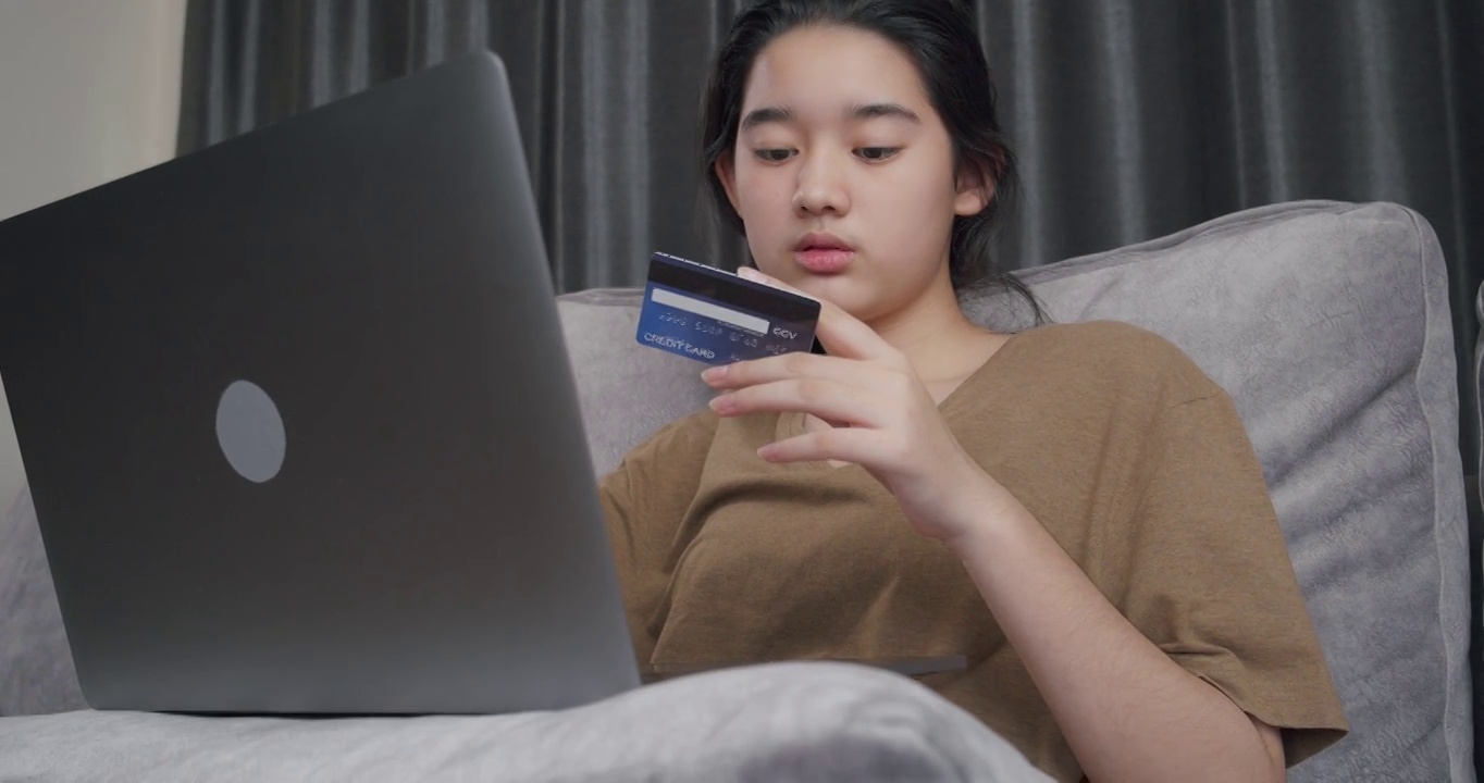 十几岁的女孩在网上购物网站使用信用卡购物。电子商务交易