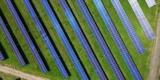 当代太阳能农场。一排排的蓝色阳光电池坐落在绿色的田野上。创新的清洁阳光能源收集器。鸟瞰图。轨道的看法。