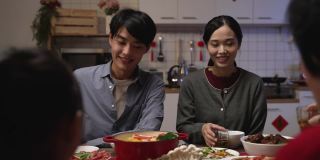选择焦点的快乐年轻的亚洲夫妇喝茶敬酒他们的家人在中国农历新年团圆饭