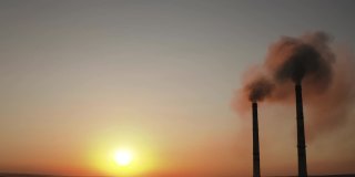 日落时的黑色烟斗。夜晚天空的背景是工厂烟囱排放的污染物。带着大烟斗的工业区。环境问题。空气污染的概念。