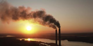 日落时工厂污染环境。有毒的企业烟囱管映衬着夜空背景释放出黑烟。在自然界中产生有害物质的烟斗。