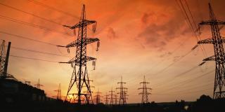 日落时高高的电塔。高压电线通过电缆分配电力。晚上有金属塔的配电站。缓慢的运动。