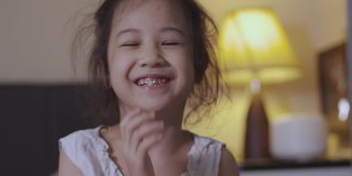4张照片，可爱的5岁亚洲女孩在卧室里笑着笑着，脸上带着滑稽和幸福的表情，表现出积极的情绪和漂亮孩子的快乐时刻。