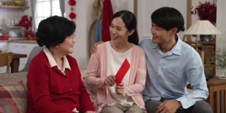 在现代化明亮的客厅里，满怀感激的亚洲年轻夫妇在春节期间给年迈的母亲送红包
