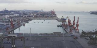 日落时分，一艘满载集装箱的船停靠在现代商业码头上装卸货物