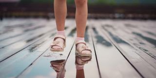女孩在木甲板上的雨水坑里跺脚