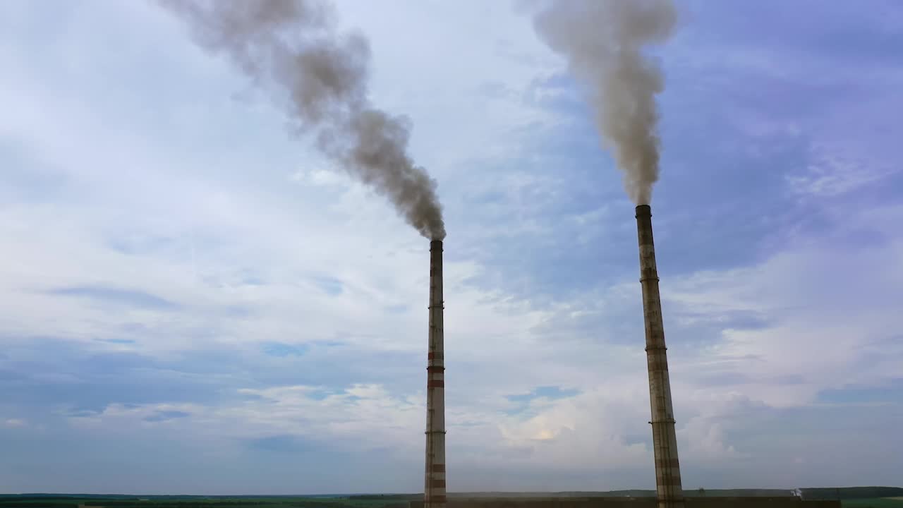 企业的烟囱管映衬着天空的背景释放出黑烟。蓝天下的危险烟雾。工厂污染环境。