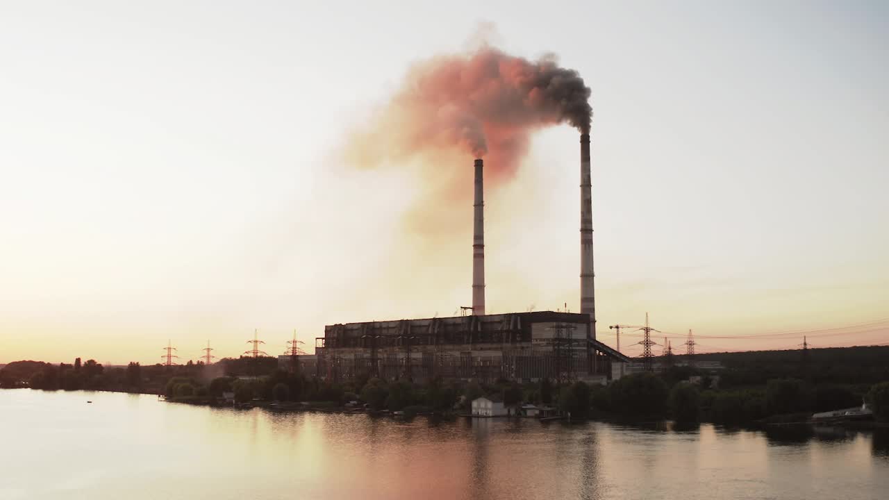 一股股黑色的烟雾释放到大气中。日落时分，工厂排放的有害气体污染了河边的空气。生态灾难。