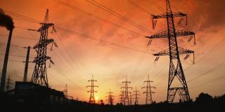 日落时分的配电站。在明亮的傍晚天空背景下，高钢铁塔和电线。Hi-voltage电线。上升了。